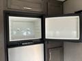 Interior view of a refrigerator and freezer compartment in a 2021 Jayco Jay Flight with doors open revealing empty shelves and no contents
