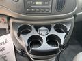 A black cup holder console with space for six cups or bottles and a circular compartment in the center in a 2008 Ford Econoline