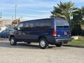 2013 Ford E-350 Super Duty van in blue, featuring a spacious body design and rear windows, positioned with a sturdy build and high wheels