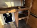 A 2015 GMC Savana with a wooden interior setup featuring shelves and a doorway leading to the front cabin area