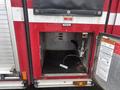 A red 2006 E-One Typhoon fire truck with an open compartment revealing a black grate and various equipment connections inside