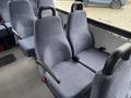 Two rows of blue upholstered seats inside a vehicle, with armrests and seatbelts, designed for passenger seating in a 2018 Chevrolet Express