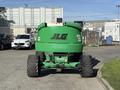 A 2015 JLG 450AJ lift is positioned facing forward showcasing its green body and black logo on the rear while mounted on large tires