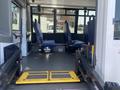 Interior of a 2020 Chevrolet Express showing two blue seated areas and a wheelchair lift with yellow ramp on the floor