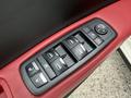 Close-up of the door control panel of a 2016 Maserati Ghibli featuring window controls and mirror adjustment buttons on a red leather armrest