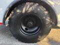 A close-up view of a large black tire mounted on a Freightliner M2 106 truck with visible tread patterns and a metal rim