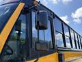 A close-up view of the side mirror and window of a yellow 2011 Freightliner B2 school bus showcasing its metallic and glass features