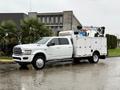 A 2024 RAM 5500 work truck with a utility body and mounted hydraulic boom lift on the bed