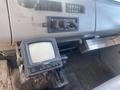 A 1997 Freightliner FL70 interior featuring a dashboard with controls and a vintage monitor on the center console