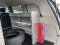 A 2014 RAM Cargo Van interior featuring a metal storage shelf a red toolbox and a black tire on the floor