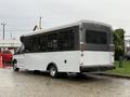 A 2019 Chevrolet Express bus with a primarily white body and black accents parked with large windows on the sides