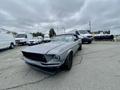 A 1968 Ford Mustang two-door convertible in gray with a dark interior parked in a lot with other vehicles around it
