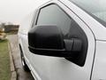 Close-up of the side mirror of a white 2018 Ford F-150 with raindrops on the surface