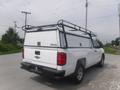 A white 2015 Chevrolet Silverado 1500 pickup truck with a black roof rack and a camper shell on the bed