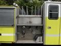 A 1995 Freightliner FLL086 with a bright yellow exterior featuring storage compartments and several fire hoses mounted on the side