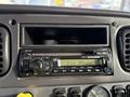 A dashboard of a 2015 Freightliner M2 featuring a radio with buttons and a display showing "CLK AM"