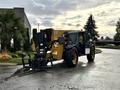 A 2014 Caterpillar TL1055C telehandler with a lifting arm and forks attached parked on a wet surface