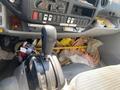 The interior of a 2014 Hino 195 showing the gear shift lever with gear indicators and a cluttered floor filled with various items like ropes and tools