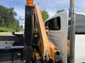 A 2011 International 4300 with an orange boom arm extended from the side of the vehicle