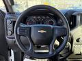 Steering wheel of a 2024 Chevrolet Silverado 1500 featuring controls on the left side and the Chevrolet logo at the center