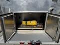 A storage compartment of a 1994 Volvo FE 42 containing a yellow hose with a black strap and a metal tool