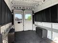 Interior of a 2017 RAM Promaster van with a spacious cargo area featuring white walls and dark storage bins along the sides