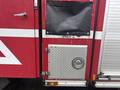 A 2006 E-One Typhoon fire truck with a red and white exterior featuring a door with a black panel and a diamond plate utility compartment with a round handle and light.