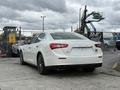 A white 2016 Maserati Ghibli with quad exhaust tips parked with a sleek design and sporty wheels