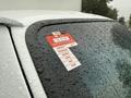 A 2022 Ford Econoline with raindrops on its window showcasing a red and white certificate of approval sticker with months listed from January to June