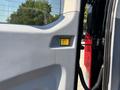 Interior door panel of a 2016 Ford Transit 150 featuring a yellow button next to a red light