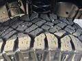 Close-up of a rugged tire tread featuring deep grooves and prominent patterns designed for traction on various surfaces