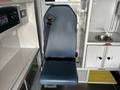 A blue upholstered seat with a safety belt positioned in a vehicle interior featuring storage compartments and a small sink