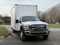 A 2012 Ford F-550 with a white cargo box and chrome front grille parked on a driveway