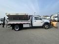 A 2016 RAM 5500 dump truck with a metal bed and front plow attachment parked in a lot