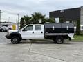 A white 2016 Ford F-550 Super Duty truck with a black utility bed and dual rear wheels parked on a concrete surface