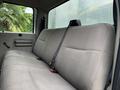 The image shows the rear seating area of a 2010 Ford F-550 Super Duty with beige fabric upholstery and seatbelt fittings