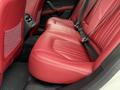Interior view of a 2016 Maserati Ghibli featuring luxurious red leather backseats with stitching details and seatbelts attached