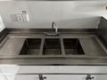 A stainless steel sink with three compartments and a faucet situated above the sink