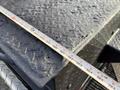 A close-up of a textured metal surface of a 2010 International 4300 truck platform with a measuring tape laid across it