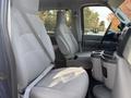 Interior view of a 2013 Ford E-350 Super Duty with two front seats featuring light gray upholstery and a central console with cup holders