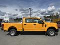 A bright yellow 2017 Ford F-250 SD with a crew cab and a bed rack in the truck bed is parked on a lot, showcasing its side profile and robust build