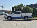 A 2017 Chevrolet Colorado pickup truck with a white and blue color scheme is parked with a utility bed and equipped with tools in the bed