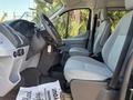 Interior view of a 2016 Ford Transit 150 with two gray seats and a dashboard featuring various controls and a steering wheel