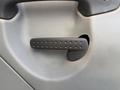 A close-up of a black door handle on a textured gray surface of a 2012 Freightliner M2 106