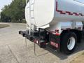 A 2010 Freightliner M2 106 tanker truck with a white cylindrical tank and black chassis visible from the rear showing red and white reflective stripes
