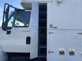 A 2008 International 4400 with an open storage compartment revealing multiple metal shelves inside