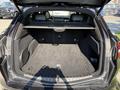 The image shows the open trunk of a 2020 Alfa Romeo Stelvio featuring a spacious interior with a flat carpeted surface and a retractable cargo cover