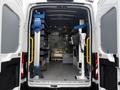 Interior of a 2023 Ford Transit van equipped with shelves tools and a workbench setup for mobile utility or service tasks