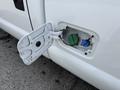 A close-up view of a fuel door on a 2011 Ford F-350 SD showing two fuel inlet ports one green and one blue