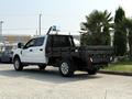 A white 2020 Ford F-350 SD with a black flatbed in the rear parked with palm trees in the background
